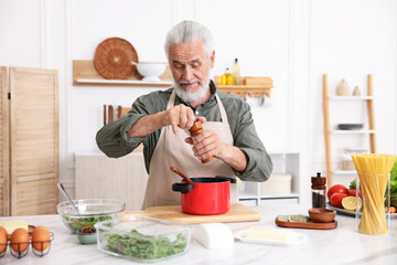 Elderly man cooking at white marble table in kitchen