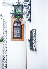 Elegant street scene featuring a vintage lantern and decorative wrought iron details against a pristine white wall, showcasing architectural beauty and charm in a tranquil setting