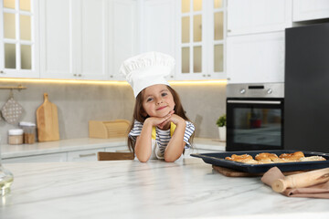 Choice of profession. Little girl with pastries pretending to be chef in kitchen