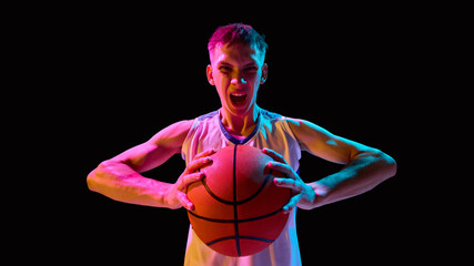 Basketball player screaming with ball in neon lights showing raw emotion. Concept of advertising, branding, sports identity, motivational campaigns, and powerful lifestyle visuals.