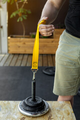 Close-up of a hand gripping a yellow strap for armwrestling supination exercise with a weight. Ideal for home training, fitness and strength sport concepts. Focus on forearm, wrist, and grip strength.