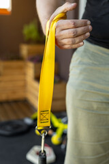 Close-up of a hand gripping a yellow strap for armwrestling supination exercise with a weight. Ideal for home training, fitness and strength sport concepts. Focus on forearm, wrist, and grip strength.