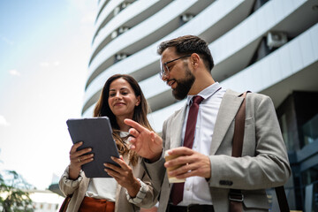 Businesspeople using digital tablet and discussing in front of office building