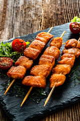 Fried salmon skewers with white dip on stone board on wooden table	