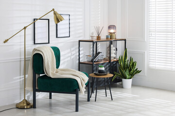 Stylish living room with lamp, armchair, side table and shelving unit. Interior design