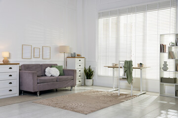 Soft sofa, table, dressers and houseplant in living room. Interior design