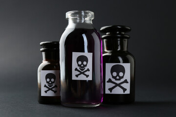 Bottles of poison with warning signs on grey background, closeup
