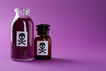 Bottles of poison with warning signs on purple background, closeup. Space for text