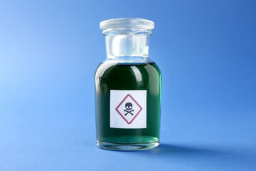 Bottle of poison with warning sign on light blue background, closeup