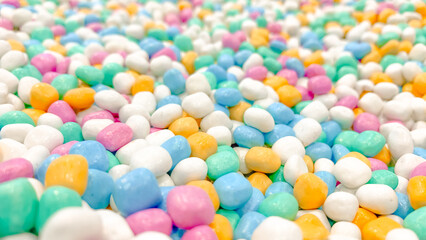 Pastel decorative stones arranged close together, colorful small pebbles forming abstract texture and background for decoration or design.