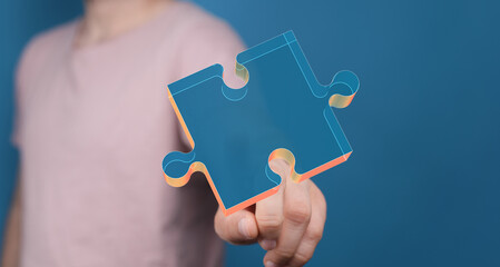 Image of a hand holding a glowing puzzle piece, representing solutions, connection, and teamwork.
