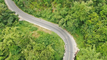 aerial view of a winding mountain road in a lush, forested area