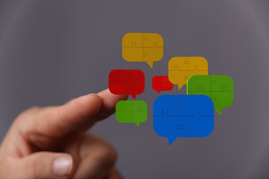 Hand interacting with puzzle speech bubbles. Concept of communication, discussion, teamwork, and social networking.  Great for marketing and sal