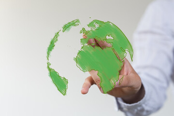 A hand interacts with a vibrant green digital sketch of the Earth, symbolizing global environmental...