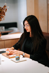 Fototapeta premium Woman enjoying coffee and dessert in a modern cafe setting during the afternoon