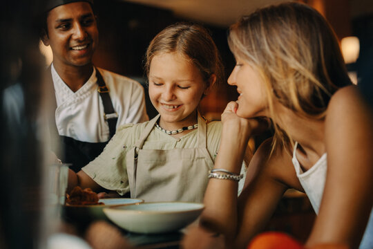 Smiling child enjoying a meal with family and a friendly chef
