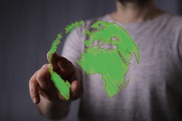 Person interacts with a digital green world, symbolizing eco-friendly tech and global solutions.