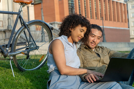 Interracial couple studying learning online together in park - Powered by Adobe