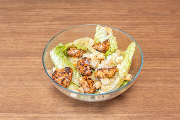 Grilled chicken Caesar salad with crispy homemade croutons, fresh romaine lettuce leaves, and a creamy Caesar dressing sprinkled with Parmesan cheese.
