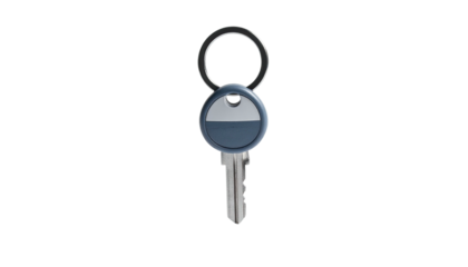 Isolated metal key on a ring, with a dark blue fob, against a black backdrop