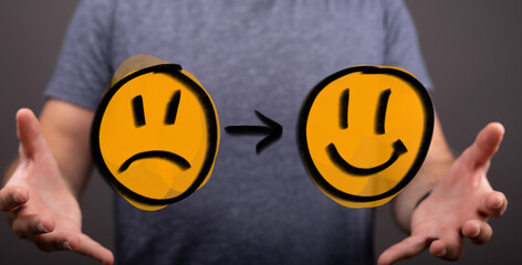 Concept showing emotional transformation from sadness to happiness with a hand holding drawn emoticons, symbolizing positive change, mood improv