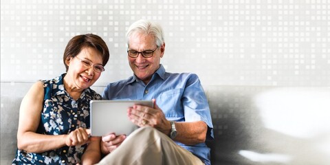 Senior couple using a digital device in a living room
