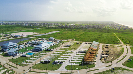 Sandy shoreline beach and RV resort in Bolivar Peninsula, Texas with clubhouse, pool, palm-lined...