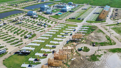 HOA-managed beach rental community near Bolivar Peninsula, Texas, swimming pool, scenic ponds. Timber stilt house under construction near RV concrete pads, palm trees, vacant land for expansion