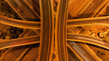 Aerial drone slow shutter night shot of illuminated multilevel junction motorway with light traffic...