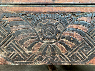 Close up of ethnic tribal and traditional abstract carving on a wood panel, in black, brown, and redwood color paint. Antique and retro engraving. Seamless background texture.