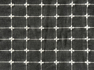 Close up of black and white cotton fabric in floral and net pattern. Suitable for clothing and upholstery. Seamless background texture.