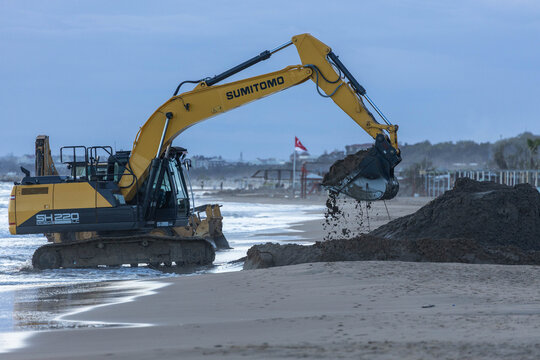Evrenseki, Antalya, Turkey - April 3 2025: Sumitomo crawler excavator moving wet sand from shoreline to beach as part of coastal land reclamation and development project.

