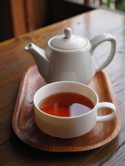 Fototapeta premium White teapot and cup of hot tea on a wooden tray