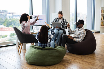 Diverse group of adults in modern office interacting with virtual reality glasses, analyzing data