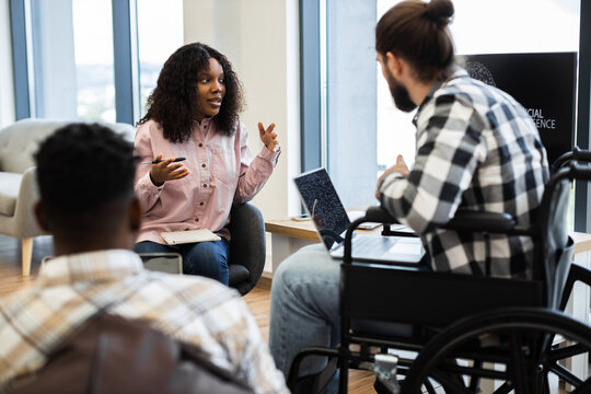 African woman business professional presenting artificial intelligence ideas to colleagues in modern workspace. Group includes diverse individuals fostering inclusivity and collaboration