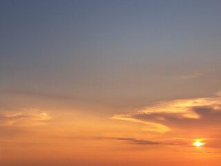 Fototapeta premium Evening sunset with an orange blue sky – White and grey clouds illuminated by the last remaining rays of the bright orange evening sun, amidst a darkening blue sky.