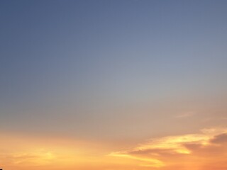 Obraz premium Evening sunset with an orange blue sky – White and grey clouds illuminated by the last remaining rays of the bright orange evening sun, amidst a darkening blue sky.