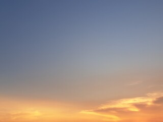 Evening sunset with an orange blue sky – White and grey clouds illuminated by the last remaining rays of the bright orange evening sun, amidst a darkening blue sky.