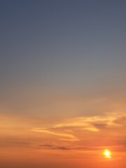 Fototapeta premium Evening sunset with an orange blue sky – White and grey clouds illuminated by the last remaining rays of the bright orange evening sun, amidst a darkening blue sky.