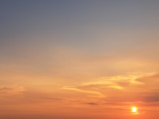 Evening sunset with an orange blue sky – White and grey clouds illuminated by the last remaining rays of the bright orange evening sun, amidst a darkening blue sky.