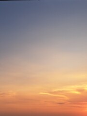 Evening sunset with an orange blue sky – White and grey clouds illuminated by the last remaining rays of the bright orange evening sun, amidst a darkening blue sky.