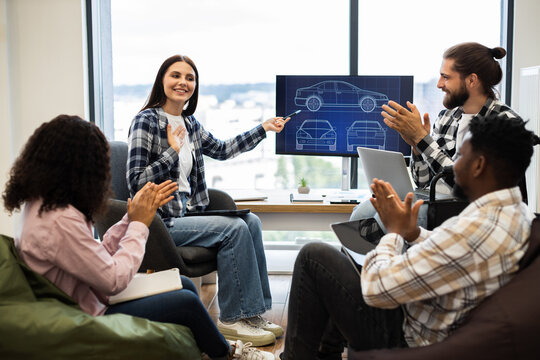 Diverse team of young adult engineers and designers having car blueprint presentation. Focus on teamwork, innovation, and collaborative design. Positive interaction includes clapping