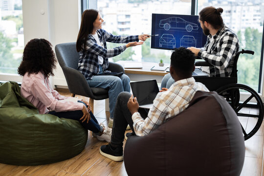 Group of diverse individuals discussing car design concepts with blueprint on monitor. Collaboration