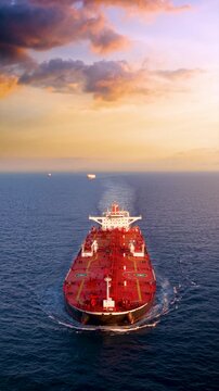Aerial front view of a heavy loaded crude oil tanker sailing over open ocean during sunset time