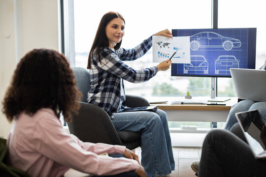 Business meeting with young adults presenting car designs and performance analysis using charts. Discussing product development, focusing on automotive concepts - Powered by Adobe