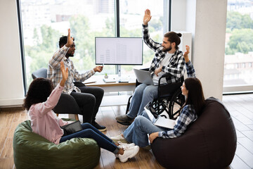 Collaborative session of young diverse team discussing plans and brainstorming ideas in office. Inclusive setting featuring teamwork, creative strategies, and innovative solutions.