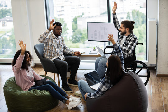 Collaborative session of young diverse team discussing plans and brainstorming ideas in office. Inclusive setting featuring teamwork, creative strategies, and innovative solutions.