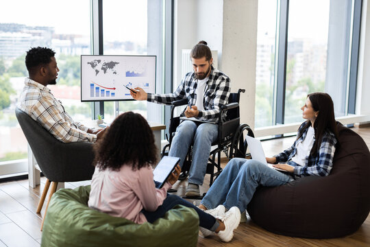 Diverse group of business professionals analyzing global trends on monitor in casual workspace. Collaborative environment highlights teamwork and discussion of data insights.