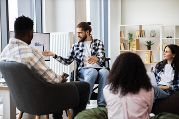 Group of adult colleagues collaborating on financial project in modern office setting. Discussing data trends displayed on screen. Individuals showcasing teamwork and diversity, including male leader.