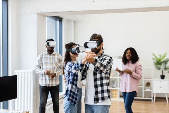 Young diverse adults in modern office using virtual reality headsets engaging in teamwork activity. Innovative approach to technology enhancing creativity and collaboration.